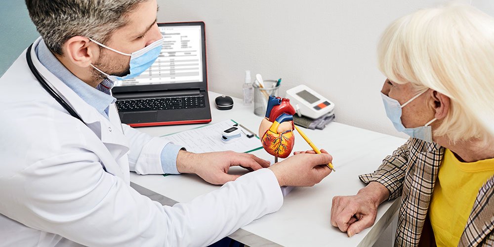 Cardiólogo explicando un modelo del corazón durante una consulta